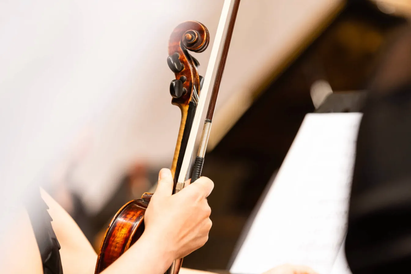 A violinist holding a violin and bow beside a music stand